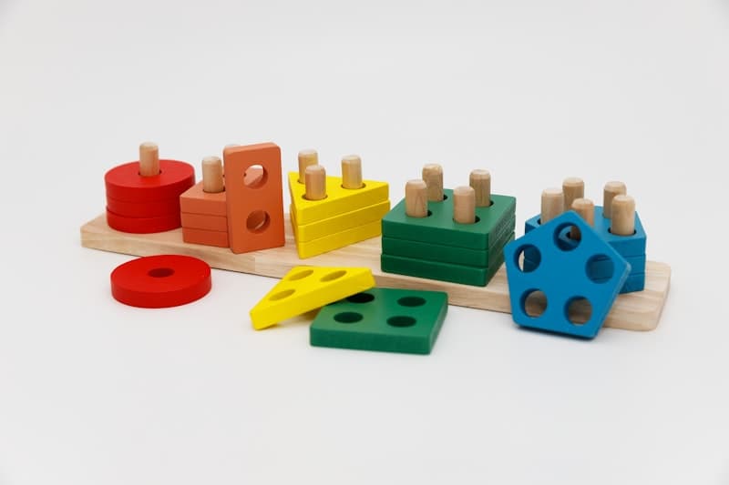 A wooden shape-sorting bench with coloured blocks resting beside its openings